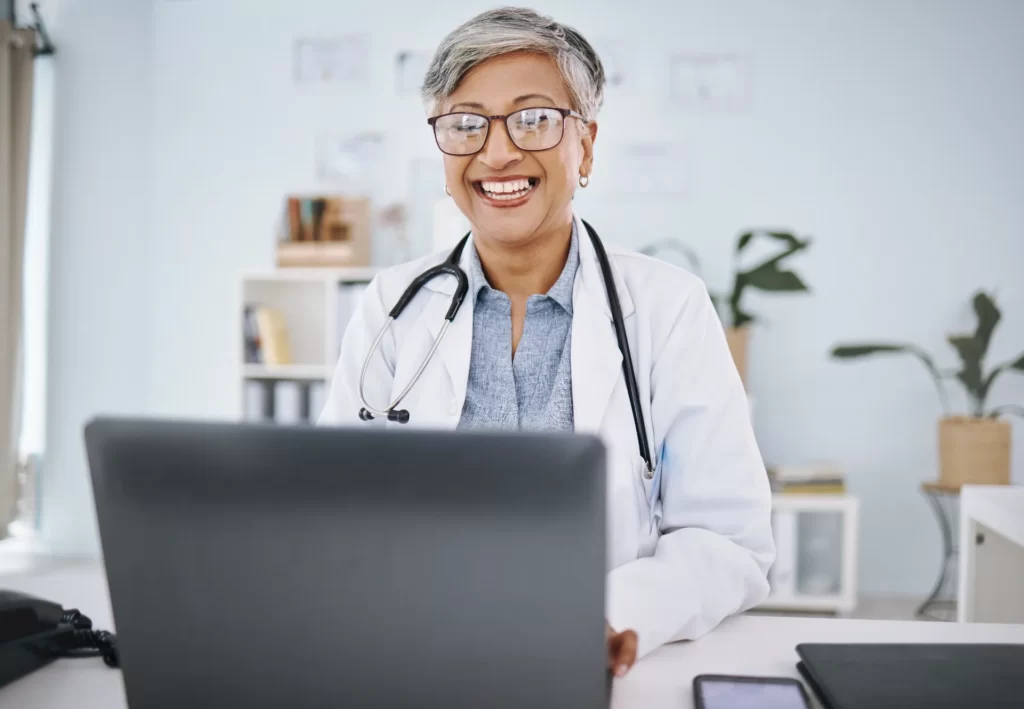 woman doctor laptop and happy in hospital office utc
