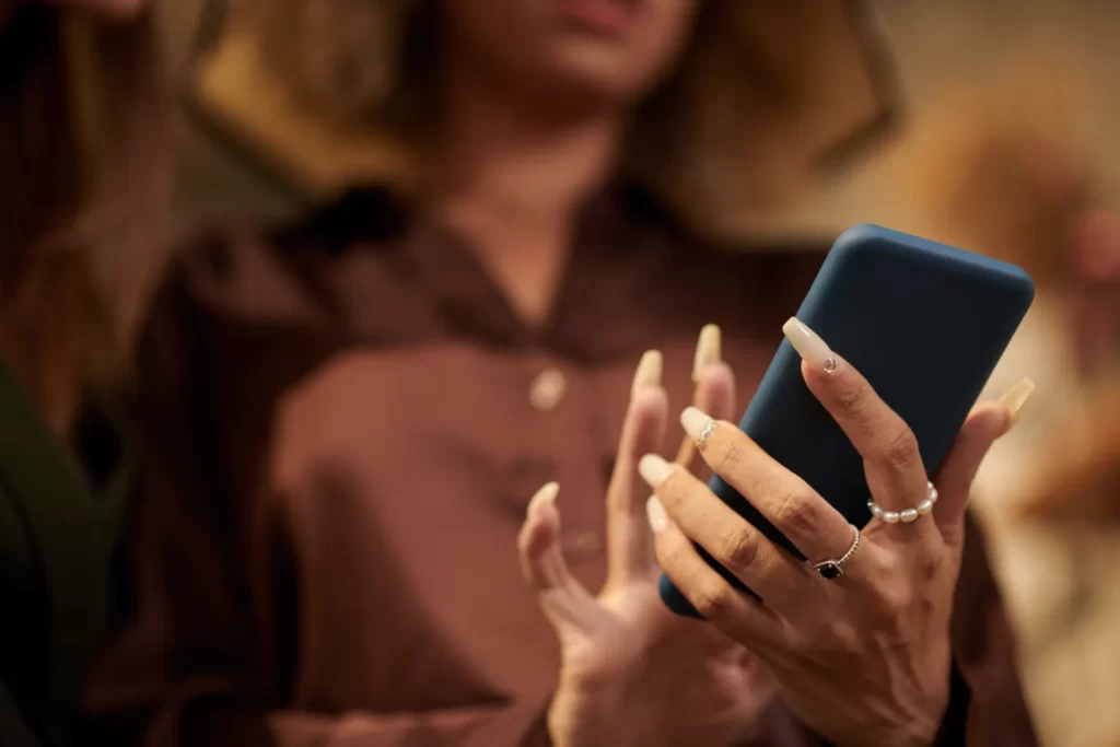 woman s hand holding a phone with long nails utc